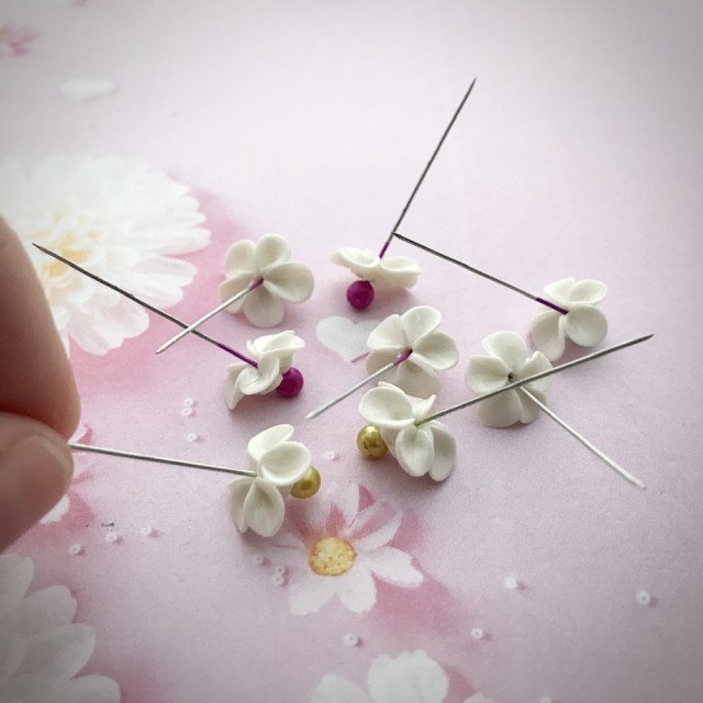 Her blir hver blomst glasert med pensel på en nål